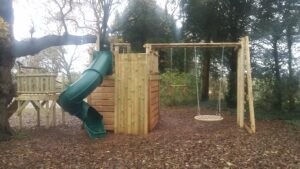 Tower, vertical climbing wall, swing set and spiral tube slide